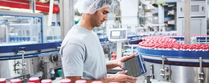 A man holding a tablet assessing data for continuous improvement in manufacturing.